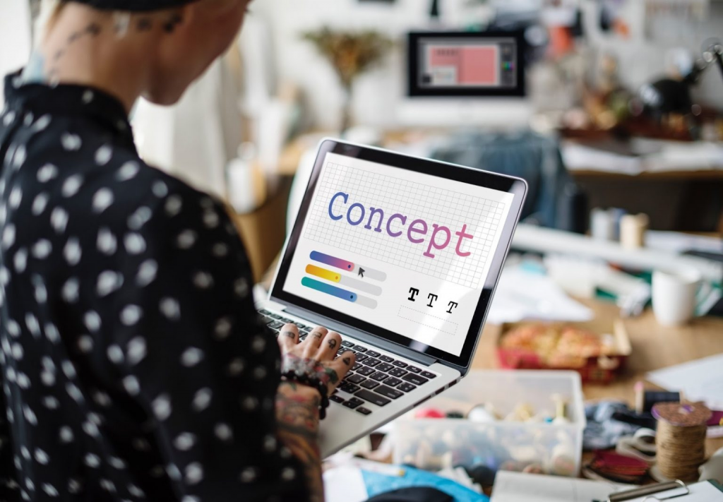 Person working on a laptop designing a concept layout with text and color elements in a creative workspace
