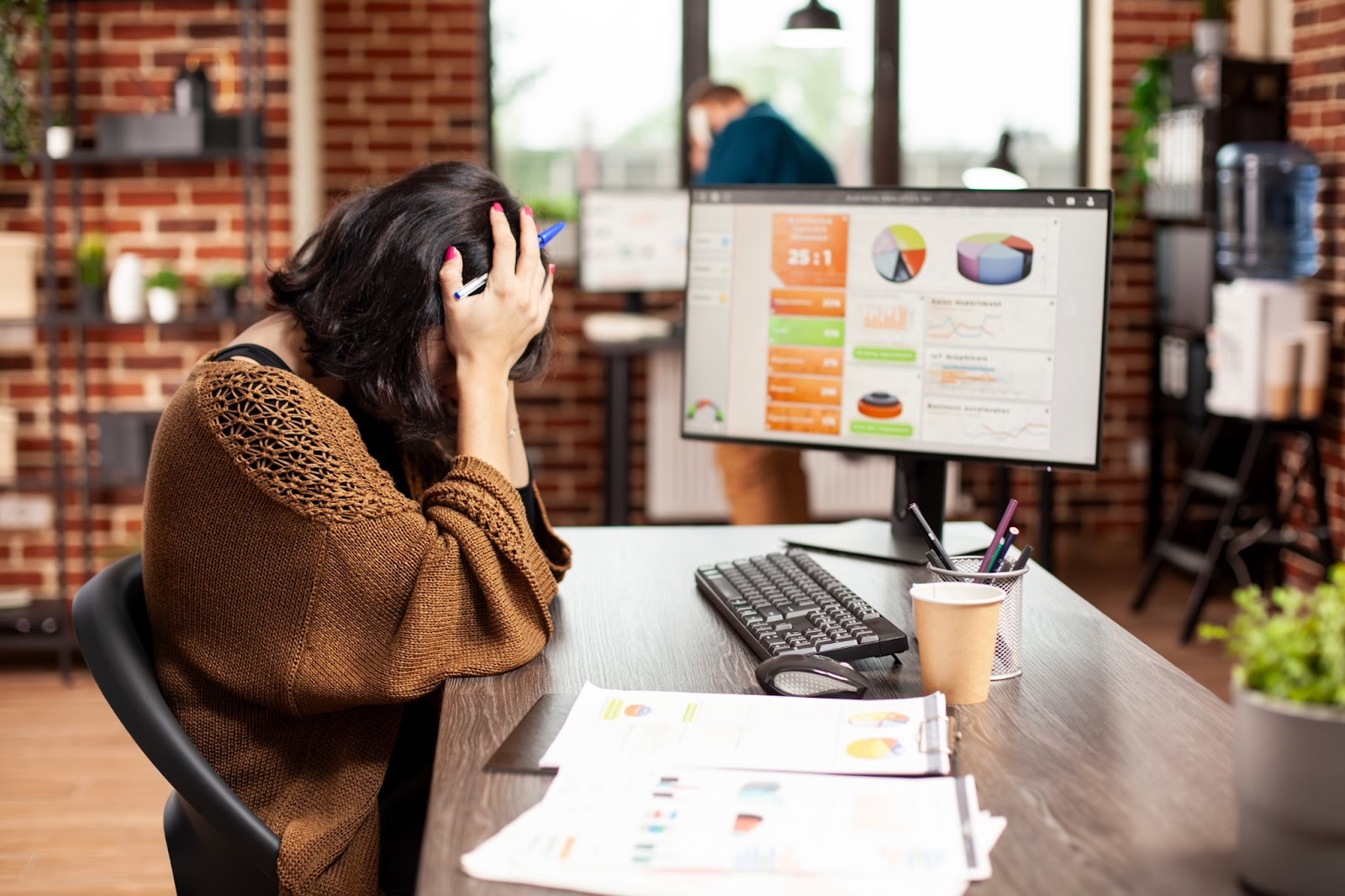 Stressed official sitting at their desk with hands covering their face, clearly stressed due to traditional SEO research. Caption: Traditioanl SEO research leads to stalled growth and frustration