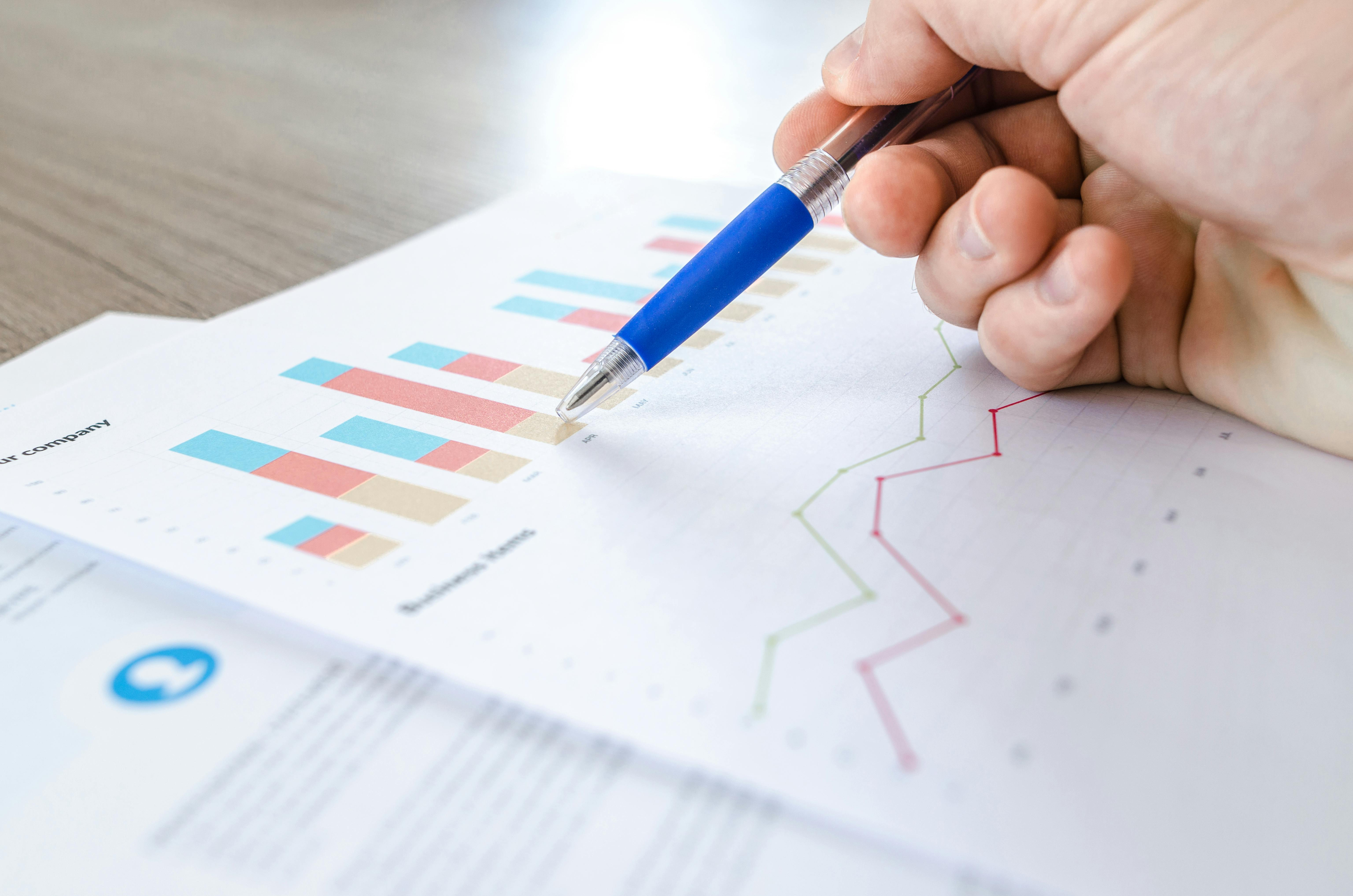Person analyzing a graph on paper with a pen, visualizing results from affordable SEO services for small businesses.