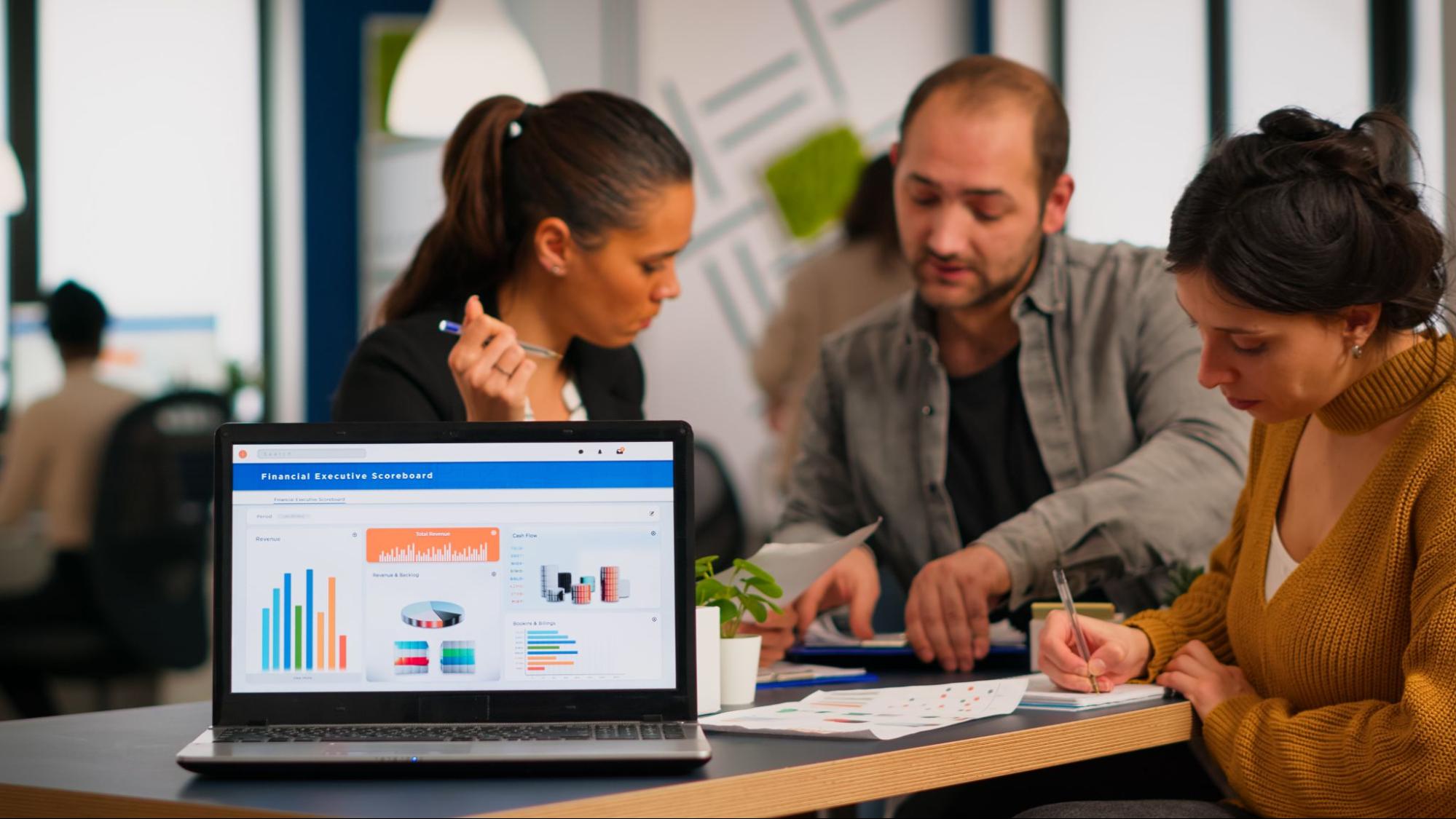 Team collaborating with charts on laptop, using an AI-powered alternative to an SEO agency for startups to drive faster growth.