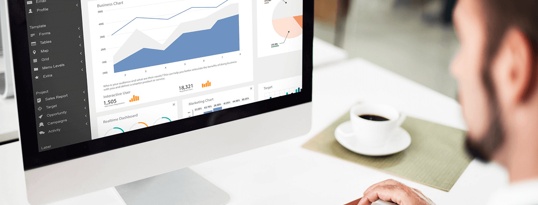 A man analyzes graphs displayed on his computer screen, focused on data interpretation