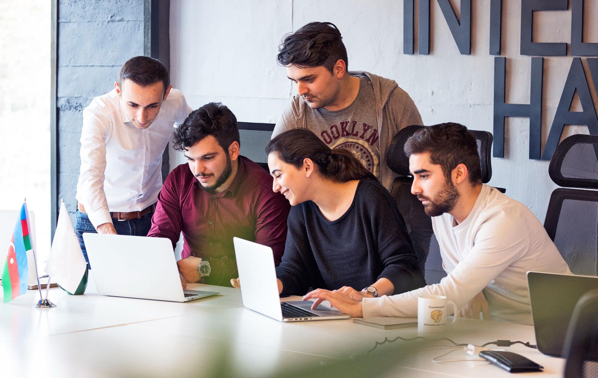 A diverse group of professionals collaborating on laptops in a modern office environment.